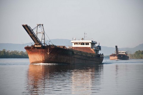 Empty sand barges returning up the estuary of the Tatai river, Cambodia